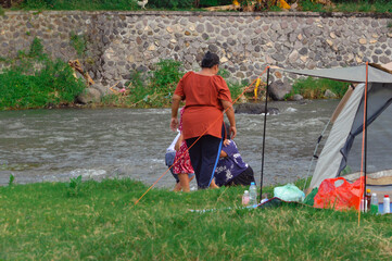 Each family member begins to slowly descend the riverbank beside their tent as they prepare to wade...