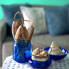 Marine style in the apartment interior - a sofa with pillows and a table with shells and fish figures.