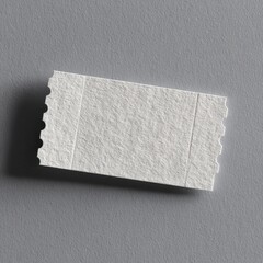A small, blank, off-white paper ticket stub with perforated edges rests on a gray background