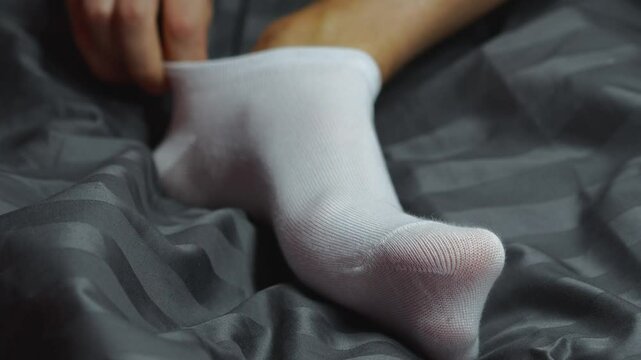Close-up of white socks on male feet in dark room