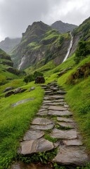 Stone path ascends verdant hillside towards cascading waterfalls nestled within imposing, mist-shrouded mountains
