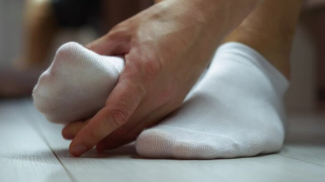 Man touching his sore foot in socks.
Fatigue of feet or foot injury.
Sore foot in white socks