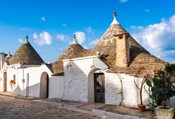 beautiful touristic view of white mediterranean buildings in old medieval Italian style of trulli in Alberobello. Antuque arhitecture in beautiful evening landscape