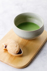 Cup of fresh matcha tea, green tea and Taiyaki, Japanese fish-shaped cake, filled with Anko or red bean on wooden plate.