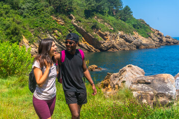 Hikers walking along coastline, enjoying scenic views on sunny day