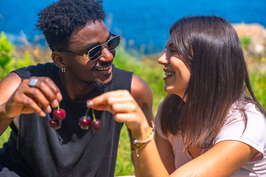 Happy couple sharing cherries in nature, enjoying summer day