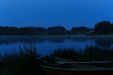 A tranquil lake at midsummer night with a rowboat on shore.