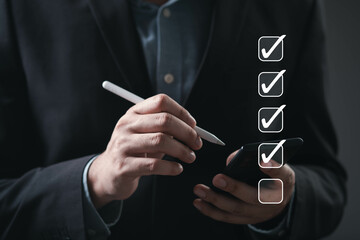 A professional person checks off tasks on a smartphone using a stylus, indicating productivity and...