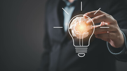 A business professional interacts with a graphic representation of a light bulb, symbolizing...