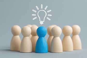 Blue peg doll with light bulb icon above, standing apart from natural wood group on gray background, symbolizing leadership, innovation, individuality, creative thinking, and visionary distinction