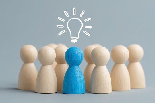 Blue peg doll with light bulb icon above, standing apart from natural wood group on gray background, symbolizing leadership, innovation, individuality, creative thinking, and visionary distinction