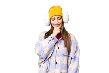 Young woman wearing winter muffs over isolated chroma key background looking to the side