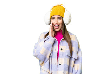 Young woman wearing winter muffs over isolated chroma key background with surprise and shocked...