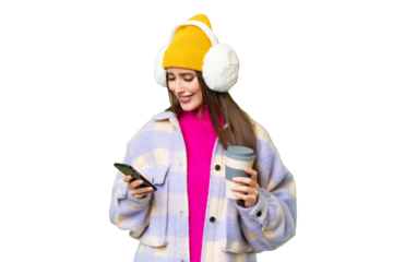 Young woman wearing winter muffs over isolated chroma key background holding coffee to take away and a mobile