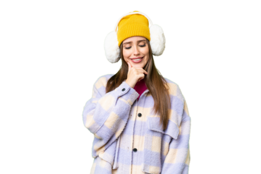 Young woman wearing winter muffs over isolated chroma key background looking to the side