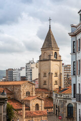 Fototapeta premium Gijon city view, Historic church tower in an urban cityscape under a cloudy sky. Asturias, Spain