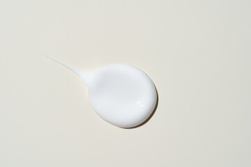 A single, thick stroke of velvety face cream on pastel beige, showcasing its lush, unblended...