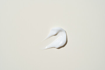 A smooth stroke of cream on a soft beige background, showing its rich texture for skincare product displays