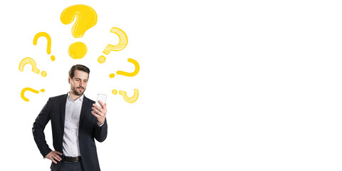 Man in business suit holding smartphone with puzzled look, yellow question marks above head, white background, concept of online problem solving