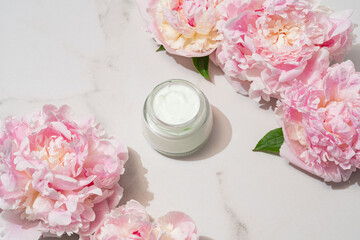 Professional product shot of open cream jar with peony accent, highlighting formula texture for...