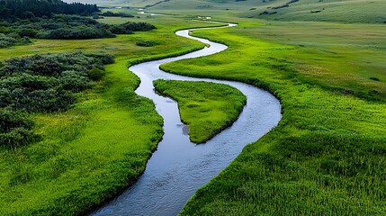 Winding river flowing through lush green meadow and rolling hills Landscape