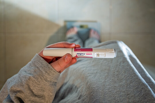 Wegovy semaglutide weight loss injection medication, being held by teenage boy standing on bathroom scales, Australia June 2025