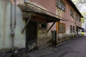 Old, weathered building with peeling paint, broken windows, and crumbling facade