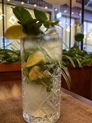 A glass with a cold mojito cocktail stands on a table in a cafe