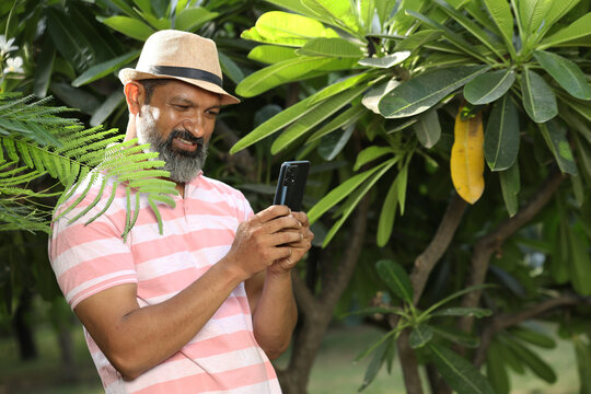 Indian Happy Beard man using mobile phone at the park. - Powered by Adobe