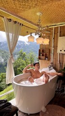 Handsome Man Relaxing in Bubble Bath with Stunning Mountain Sunset View