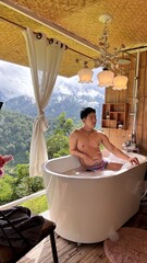 Handsome Man Relaxing in Bubble Bath with Stunning Mountain Sunset View