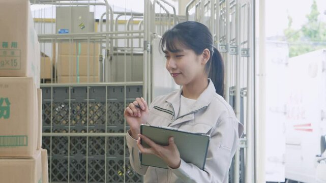 倉庫で検品する若い女性作業員