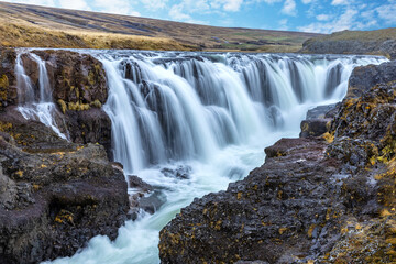 Vididalsa River cascades over the volcanic rocks at Kolufoss Waterfall in the Kolugljufur Canyon,...