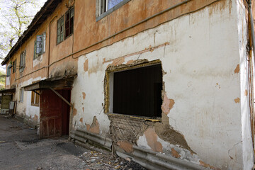 Old apartment building with cracked walls, broken window frame, and peeling paint