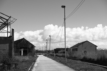 Abandoned Industrial Path

Description: A black and white photograph depicting a desolate, possibly...