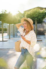 Happy woman using mobile phone in summer travel, town street. Technology urban lifestyle. Solo...