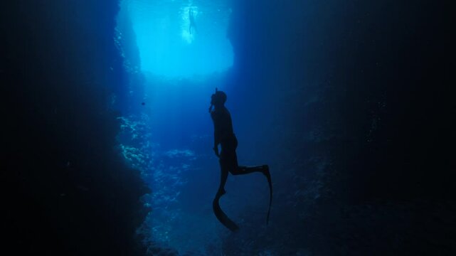 A Freediver ascending from deep cave underwater 