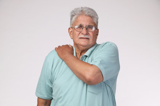 Portrait of Senior man with grey hair standing over isolated background feeling unwell and shoulder pain as symptom for joint problem health care concept.