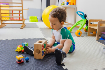 Pediatric physiotherapy. Cute boy in compression suit during play therapy in rehabilitation center...