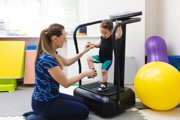 Little boy patient undergoing physical rehabilitation stands confidently wearing special orthopedic...
