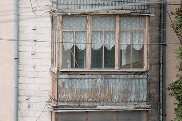 Dilapidated Balcony Window in Eastern Europe: Aged Wood, Lace Curtains, Concrete Building Facade,...