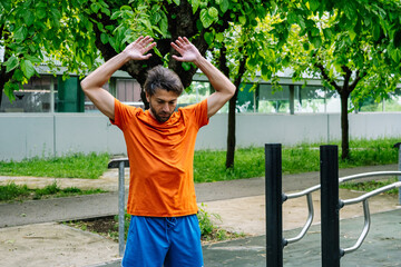 Sportsman stretching arms before calisthenics workout in outdoor gym