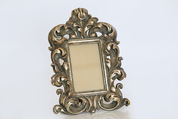 A stunning antique-style silver picture frame, standing upright, features elaborate baroque-inspired scrollwork and a beautifully aged patina that highlights its intricate details. The central rectang