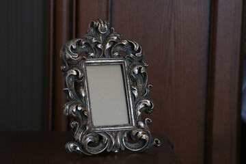 A beautifully detailed, antique-style silver picture frame stands prominently, showcasing intricate scrollwork and an aged, rich patina. The central rectangular space is intentionally left blank. © Pro Photo Factory