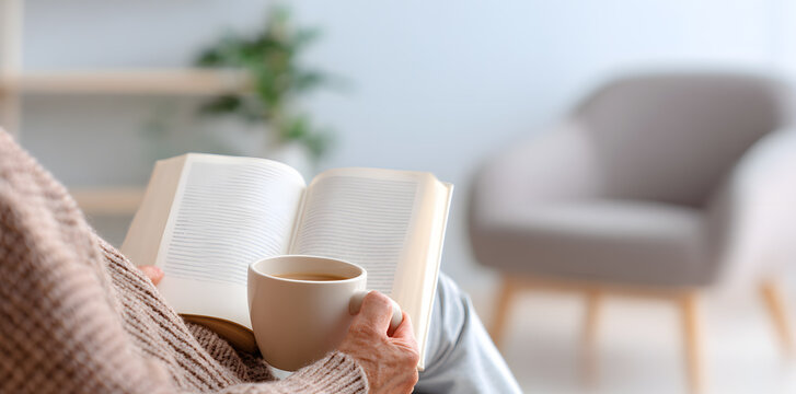 Woman relaxing with a cup of tea and reading a book at home. Peaceful and cozy scene of enjoying quiet time.