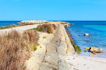 Coastal pathway meanders along a stone seawall, leading to the tranquil turquoise waters. Pathway...