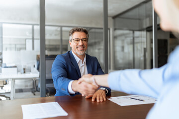Group of people satisfied with results of team work together, making handshake. Adult latin businessman man shaking hand with client, recruit female employee or business partner after signing contract
