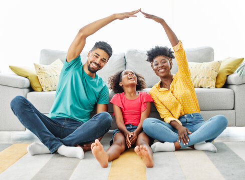 Portrait of a young family forming roof with their hands at new home