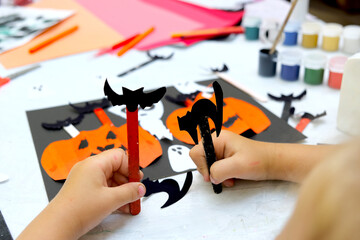 Child making paper pumpkins for the holiday, Halloween. Funny crafts from paper. Halloween decor. Handicraft. DIY. Classroom, workshop