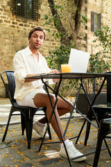Modern remote job lifestyle, Young man working remotely in outdoor cafe